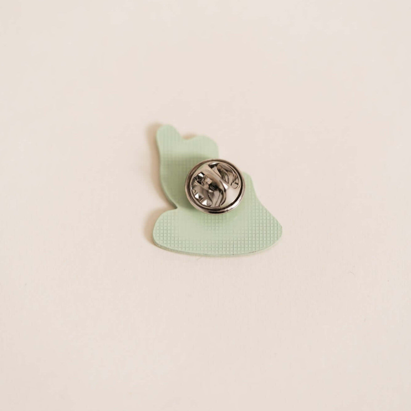 Backside of Stylish high-quality metal pin displaying surfer. Embossed with high-gloss epoxy resin coating.